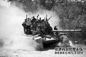 13日，进攻扎维耶市的反政府武装成员站在一辆缴获的坦克上。